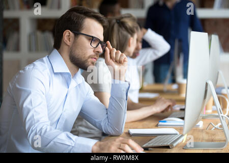 Confident pensive employee working in shared office Stock Photo