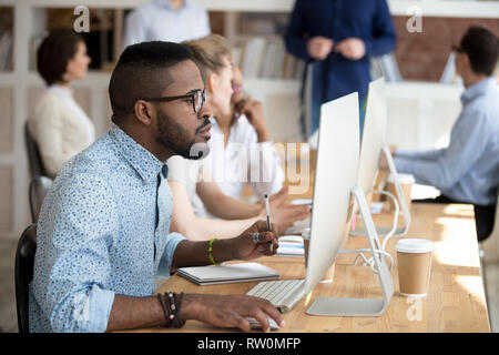 Black manager holding pen make notes on textbook using pc Stock Photo