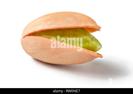 Single Turkish red pistachio, peeled green nut visible, isolated on white background. Stock Photo