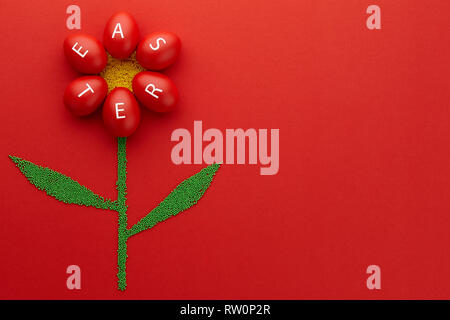 Flower shape made from Easter eggs and colorful sugar sprinkles on red background. Holiday concept. Stock Photo
