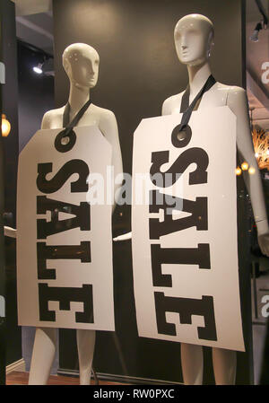 black and white sale signs hung on plain white mannequins in a shop window Stock Photo