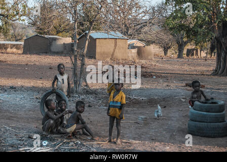 A photo of Ghanaian children posing for the camera as they are playing with old car tyres in the yard. Taken in a savanna of Ghana. Stock Photo