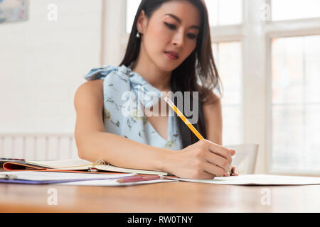 Freelancer business woman holding pen while analysing business chart in cafe. Stock Photo