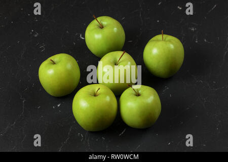 Six green / yellow apples on black marble board. Stock Photo