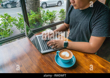 Young man working on laptop with the cup of coffed Stock Photo