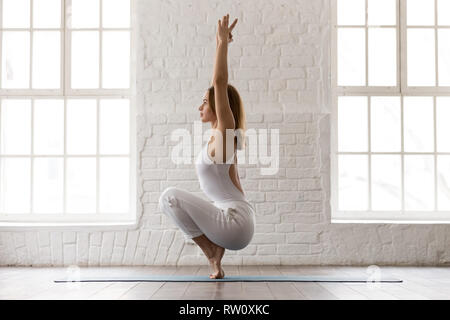 Sporty woman standing in Utkatasana pose, Squat, Chair exercise Stock Photo