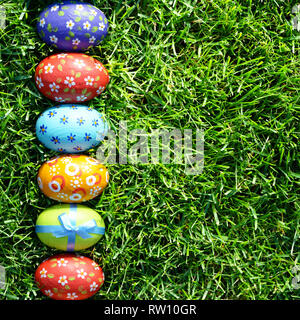 Easter eggs lying on green spring grass arranged in one lane. Space for text Stock Photo