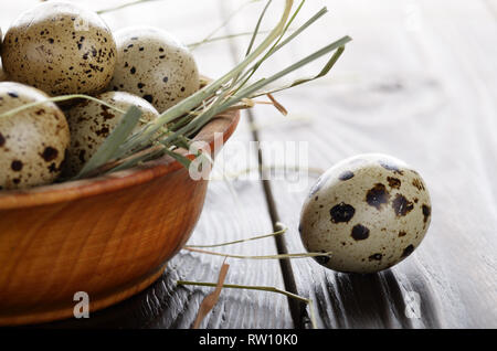 Fresh organic quail eggs in wooden bowl on rustic kitchen table. Space for text Stock Photo