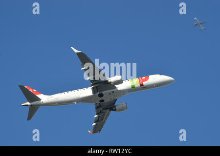 TAP Airlines plane climbing out of London City Airport as a flight inbound to London Heathrow Airport passes overhead Stock Photo