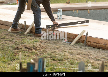 Construction Worker Checking Level On Wet Deck Cement Stock Photo