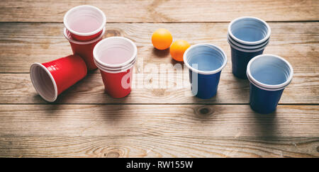 Beer pong, college party game. Plastic red and blue color cups and ping pong balls on wooden background Stock Photo