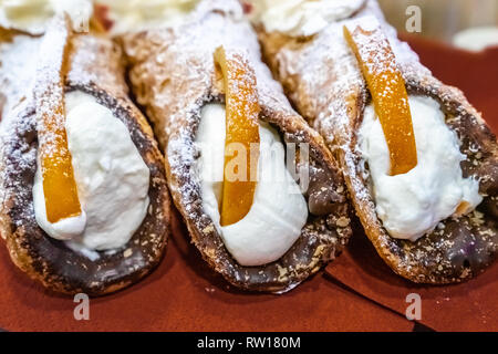 Traditional homemade Sicilian sweet, called cannoli, filling of ricotta cheese cream, sprinkled with sugar powder. With almonds and fruits. Stock Photo