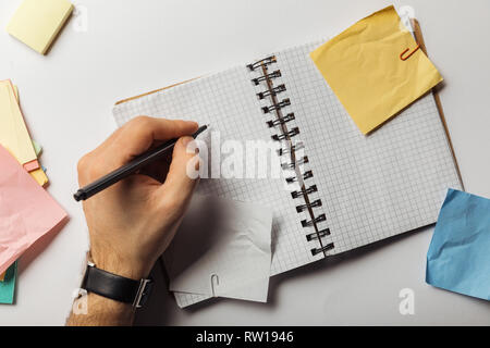 cropped view of man holding pen near squared pages in notebook near crumpled sticky notes Stock Photo