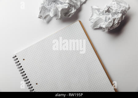 top view of notebook with blank squared page near crumpled sheets on white background Stock Photo