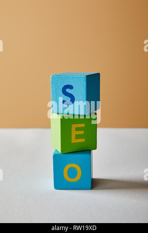 seo lettering made of multicolored cubes on white table and beige background Stock Photo