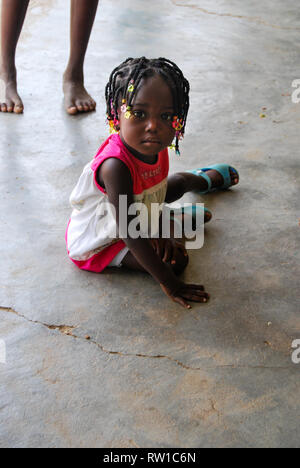 A beautiful Ghanaian girls sitting on the floor an looking seriously to the camera. Stock Photo