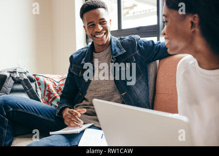 African man with his classmate at college campus. Two young people doing class assignment at campus building. Stock Photo