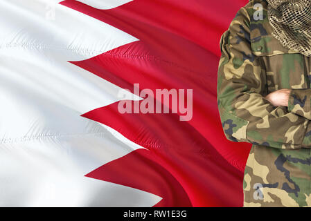 Crossed arms Bahraini soldier with national waving flag on background - Bahrain Military theme. Stock Photo