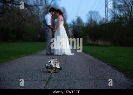 Bride and groom embracing with flower bouquet in focus Stock Photo