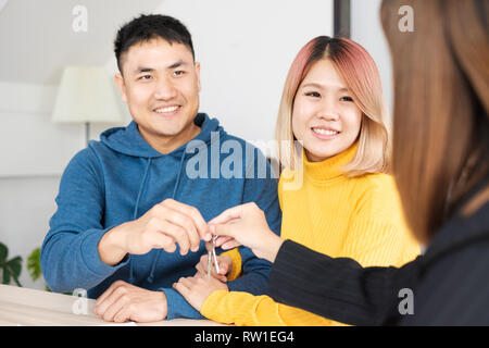 Asian happy couple getting key with realtor agent with smiling face at new home.buying new house real estate Stock Photo