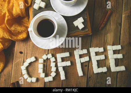 Symbolic image. Text of cube sugar. Sign coffee. Two cups of coffee espresso near sugar cube on rustic wooden table. . Top view. Stock Photo