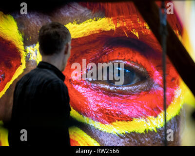 Berlin, Germany. 04th Mar, 2019. A man walks past an advertising poster for Papua New Guinea at the International Tourism Exchange (ITB) on the exhibition grounds. The ITB trade fair in Berlin is the world's largest travel trade fair with around 10,000 exhibitors from over 180 countries. It will take place from 6 to 10 March 2019. Credit: Ralf Hirschberger/dpa/Alamy Live News Stock Photo