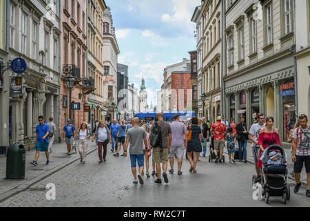 People walking and enjoying themselves along the cobblestone streets of Main Market Square in Krak—w Old Town, Lesser Poland Voivodeship, Poland. Stock Photo