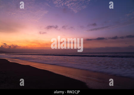 Dramatic sunset on the beach, with vivid colors of orange, pink, blue, red, gold, yellow Stock Photo