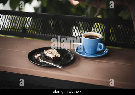 Abstract scene of coffee break meal set including black coffee, and brownie cheese cake on outdoor wood bar. Weekend morning activity with good emotio Stock Photo