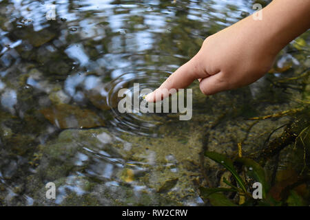 Close up finger touches water and drop of water falling and creating natural and calm waves,calmly concept - Image Stock Photo