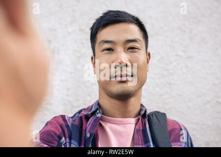 Confident young Asian man taking a selfie outside Stock Photo