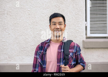 Young Asian man standing outside in the city and smiling Stock Photo