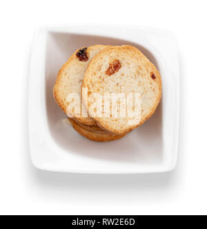 Mini round toasts of bread with raisins in white bowl. Top view. Isolated on white background. Stock Photo