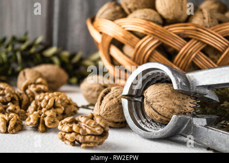 Walnuts on a white table, walnut kernels. Healthy food from walnut. Walnuts in a basket with a vine. Stock Photo