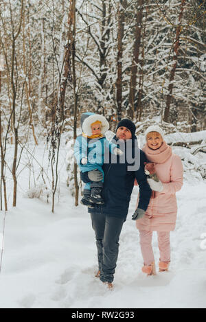 Walking family with a child. Family walks in nature in winter. Winter family walk in nature. A lot of snow. Snowy forest. Stock Photo