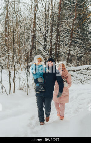 Walking family with a child. Family walks in nature in winter. Winter family walk in nature. A lot of snow. Snowy forest. Stock Photo