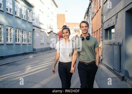 Young couple smiling while walking in the city holding hands Stock Photo