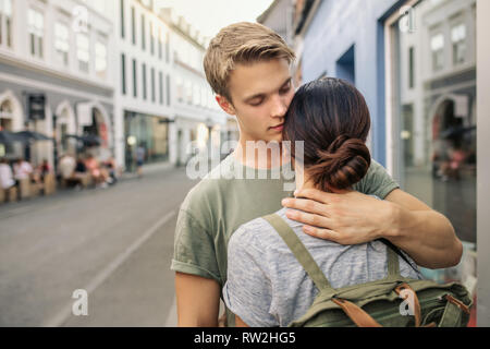 Young man kissing his girlfriend on a city street Stock Photo