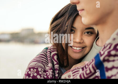 Smiling young woman wrapped in a blanket with her boyfriend Stock Photo