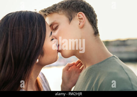 Romantic young couple sharing a kiss outside in the afternoon Stock Photo