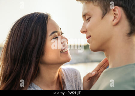 Young couple laughing while wrapped in a blanket together outside Stock Photo
