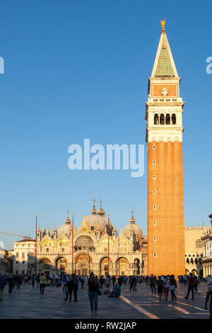 Golden sunet over Basilica San Marco and the Campanile in  Piazza San Marco, Venice, Veneto, Italy with tourists at this popular tourist attraction Stock Photo