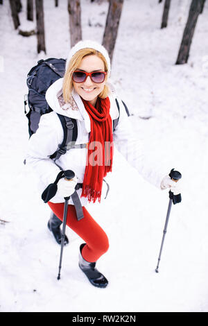 girl in red and white outfit hiking in a forest with snow on a winter day