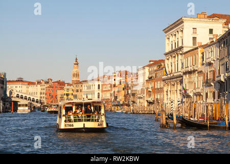 Vaporetto waterbus on the Grand Canal at sunset, Venice, Veneto, Italy with a view past ancient palazzos, palaces, to the Rialto Bridge