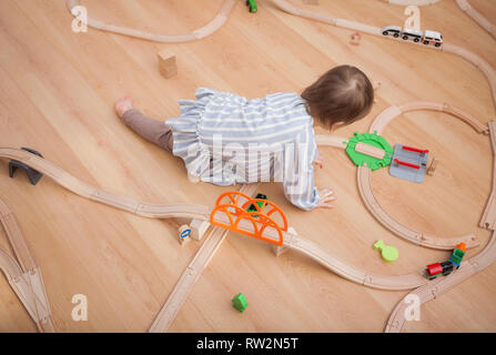 Cute kid playing with toy railway road at home