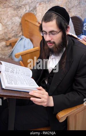 A religious Jewish young man reads a prayer book in a room adjacent to King David's Tomb in the old City of Jerusalem, Israel. Stock Photo