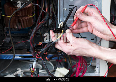 Man is testing the electrical power of power supply. Computer repair process. Technician equipment repair Stock Photo