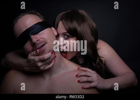 Female zombie vampire bites man in the neck Stock Photo