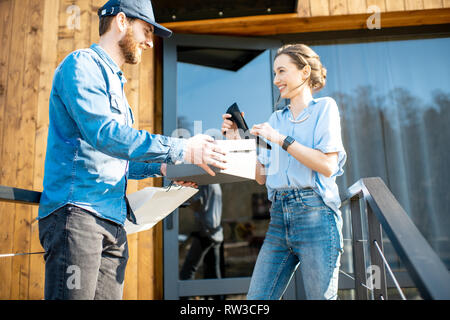 Delivery man bringing shoes home to a young woman client. Buying clothes online and delivery concept Stock Photo