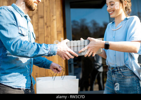 Delivery man bringing shoes home to a young woman client. Buying clothes online and delivery concept Stock Photo